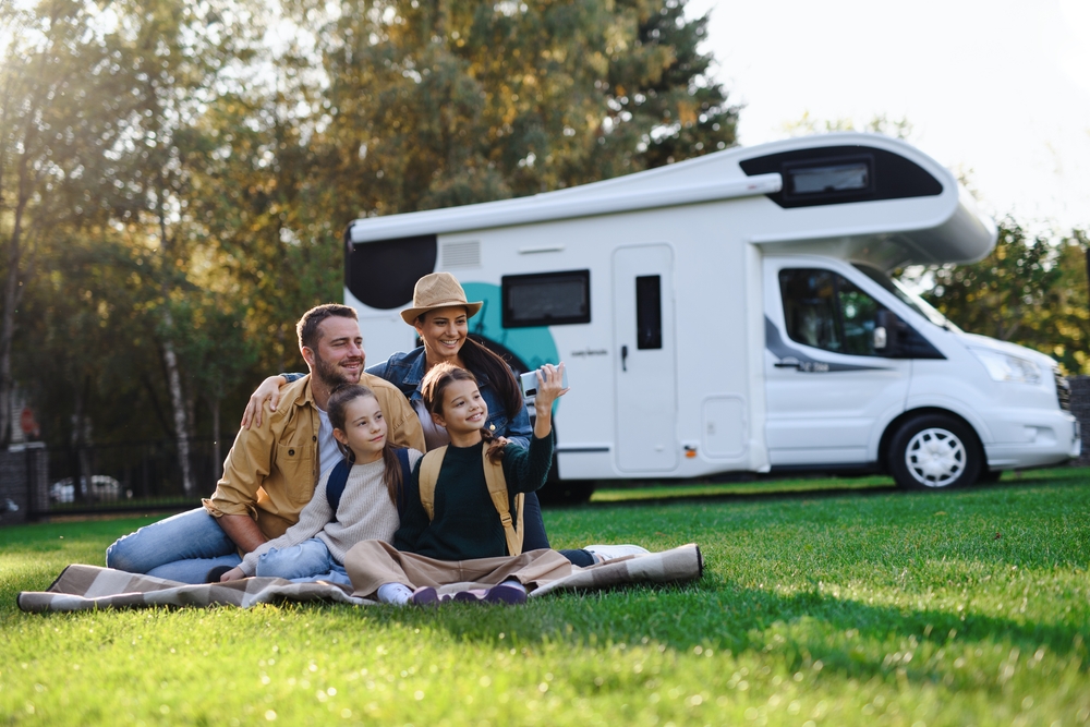 Happy family sat on grass in front of a caravan
