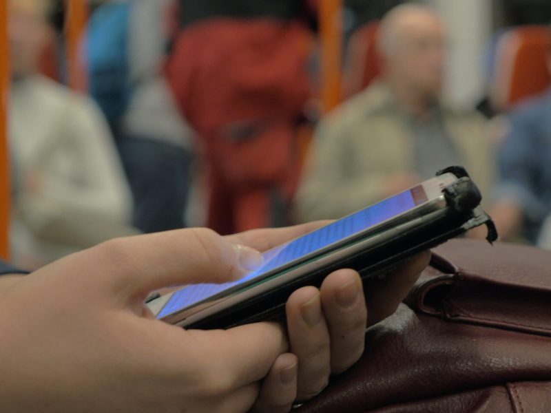 Surfing internet on cell in underground train Close-up shot of a woman commuter browsing web on smart phone during ride in subway train
